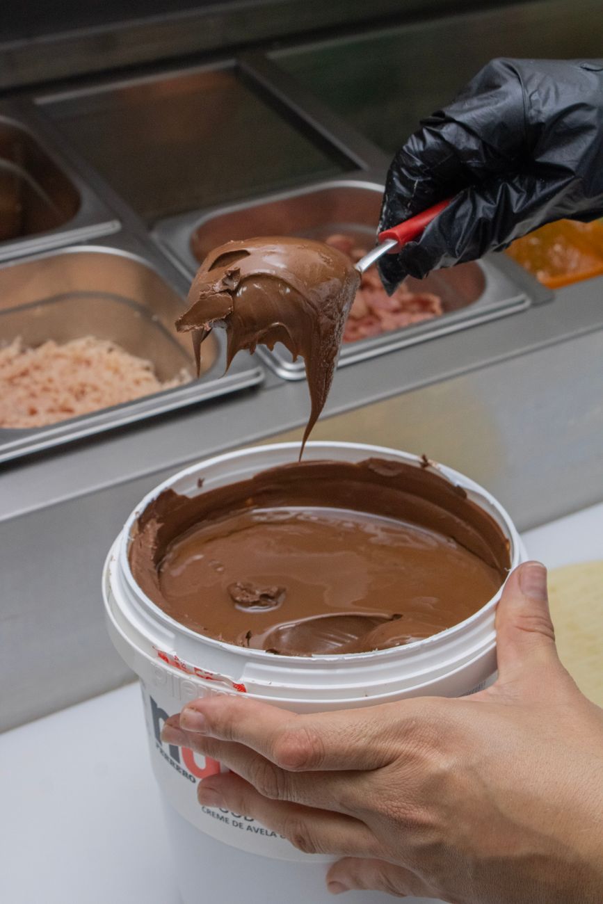 hands of a person taking chocolate spread from a bucket