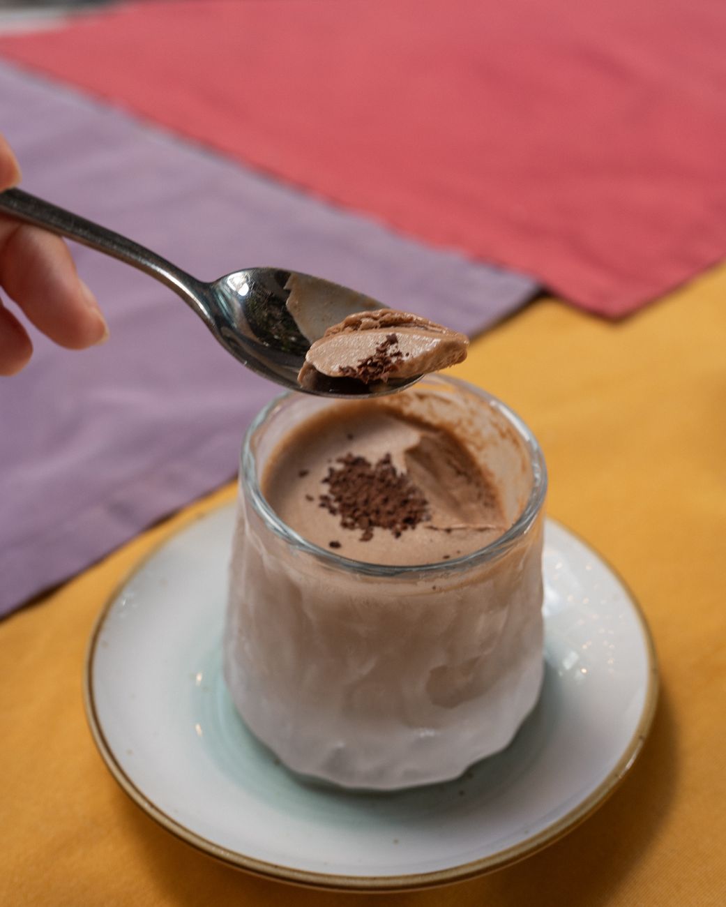 a person is spooning chocolate into a glass