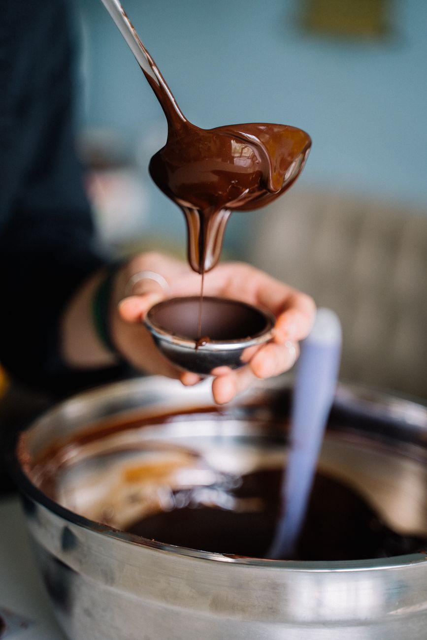 a person pouring chocolate on silver bowl